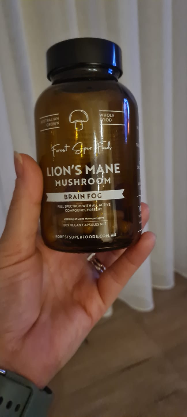 Customer holding a bottle of Lions Mane Mushroom Capsules, sharing how it helped with focus and clarity.