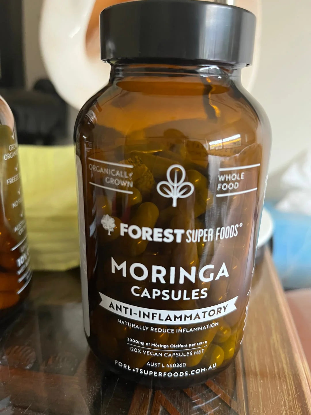 Bottle of Organic Moringa Capsules photographed outdoors.